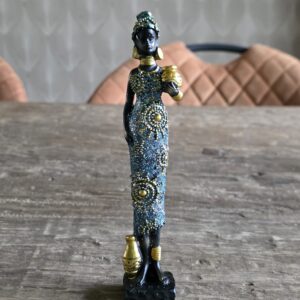 Afrikaanse vrouw gekleed in blauw en goud met een mand dragend op haar arm
