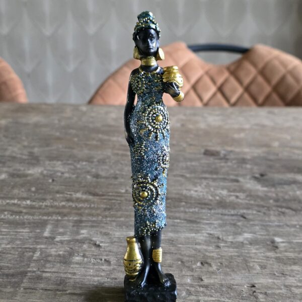 Afrikaanse vrouw gekleed in blauw en goud met een mand dragend op haar arm